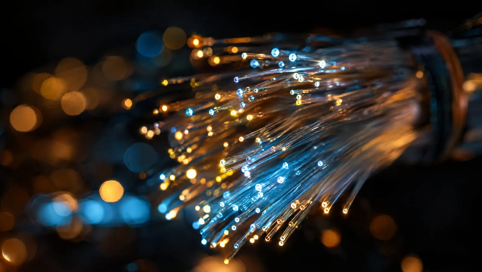 Macro photograph of fiber-optic strands glowing amber and cyan against black.