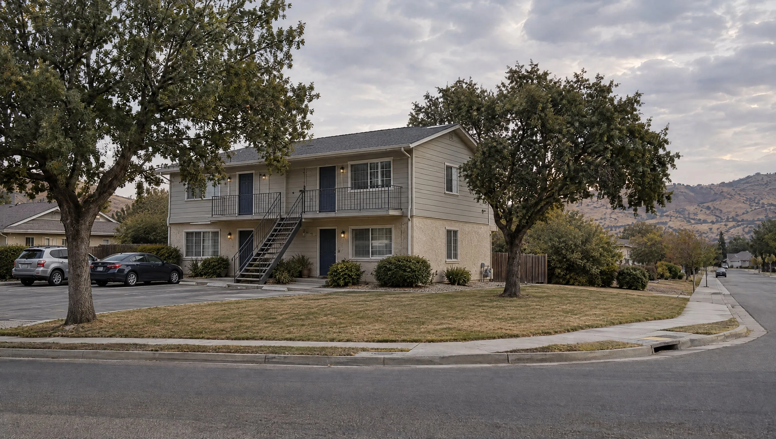A two-story fourplex with four entry doors and an exterior stair on a suburban collector road.
