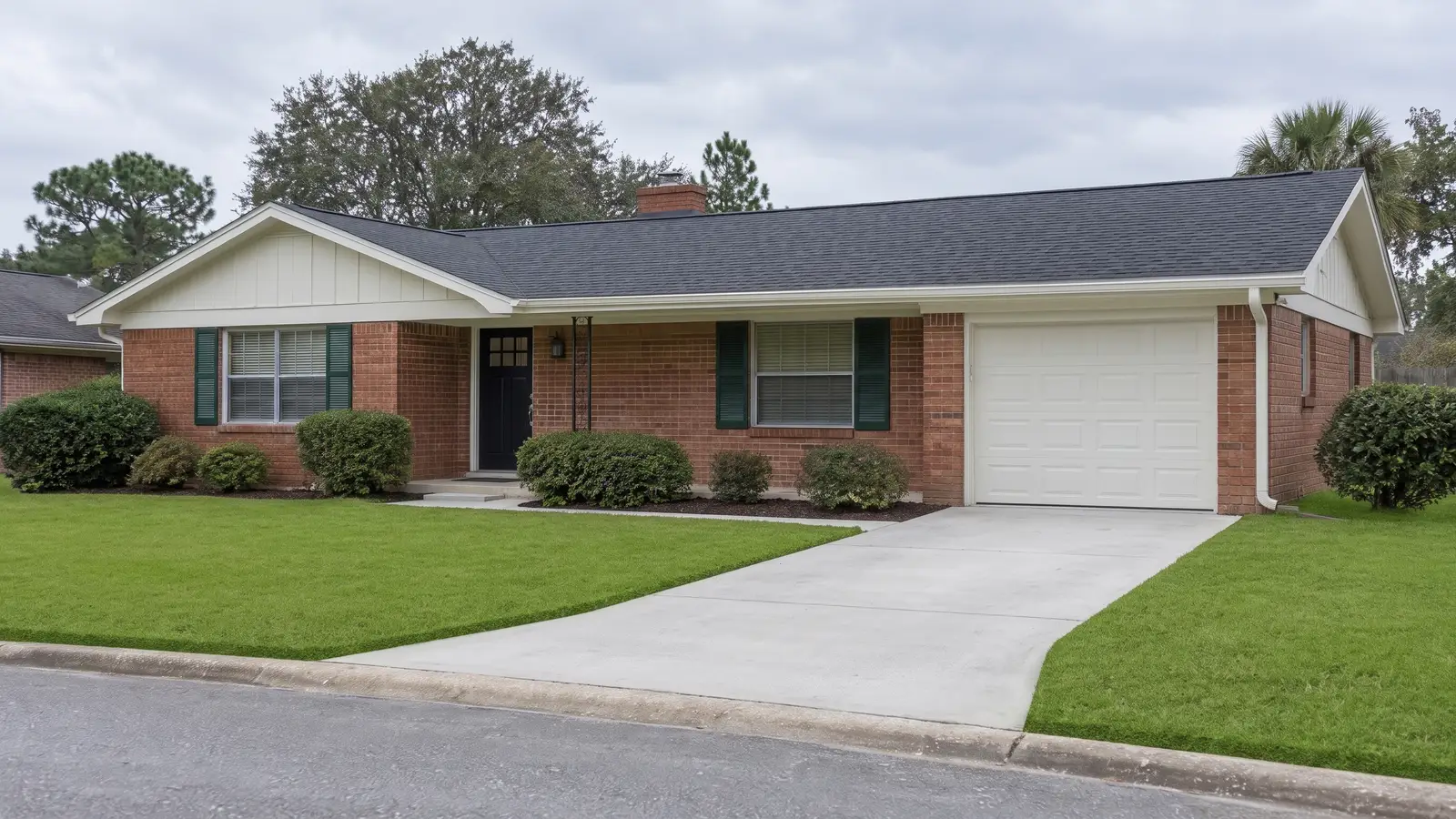 The brick ranch house freshly renovated: new charcoal roof, fresh trim paint, clean driveway.